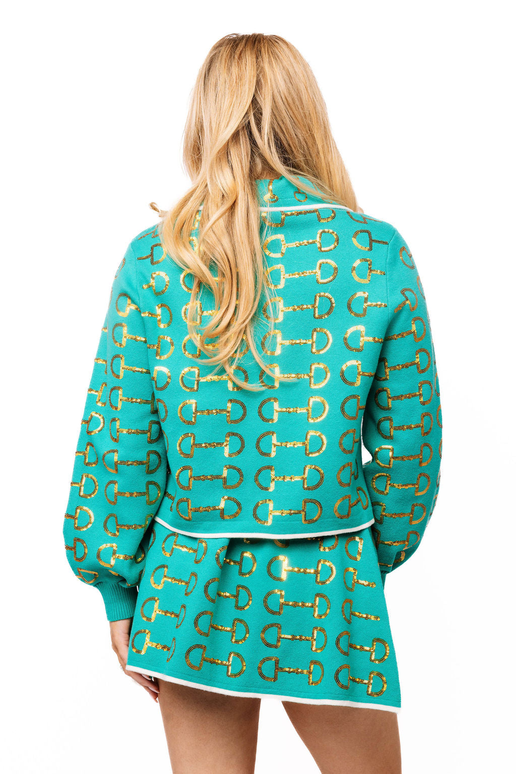 Back view of a teal Queen of Sparkles knit collar sweater with repeating gold horse-bit motifs and white trim, worn with a matching skirt.