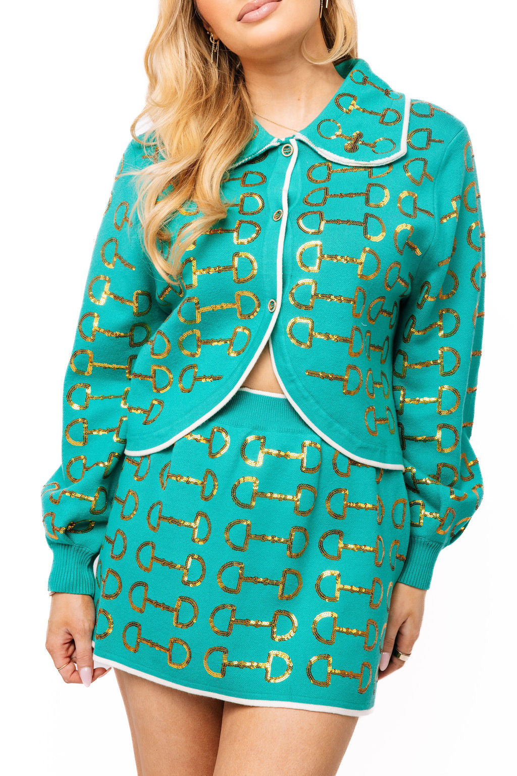 Model wearing the teal Queen of Sparkles button-up knit collar sweater with repeating gold horse-bit motifs and white trim.