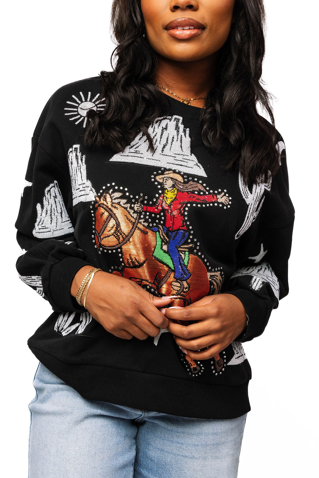 Model wearing the black Queen of Sparkles sweatshirt with a colorful bucking cowgirl design and white western motifs.