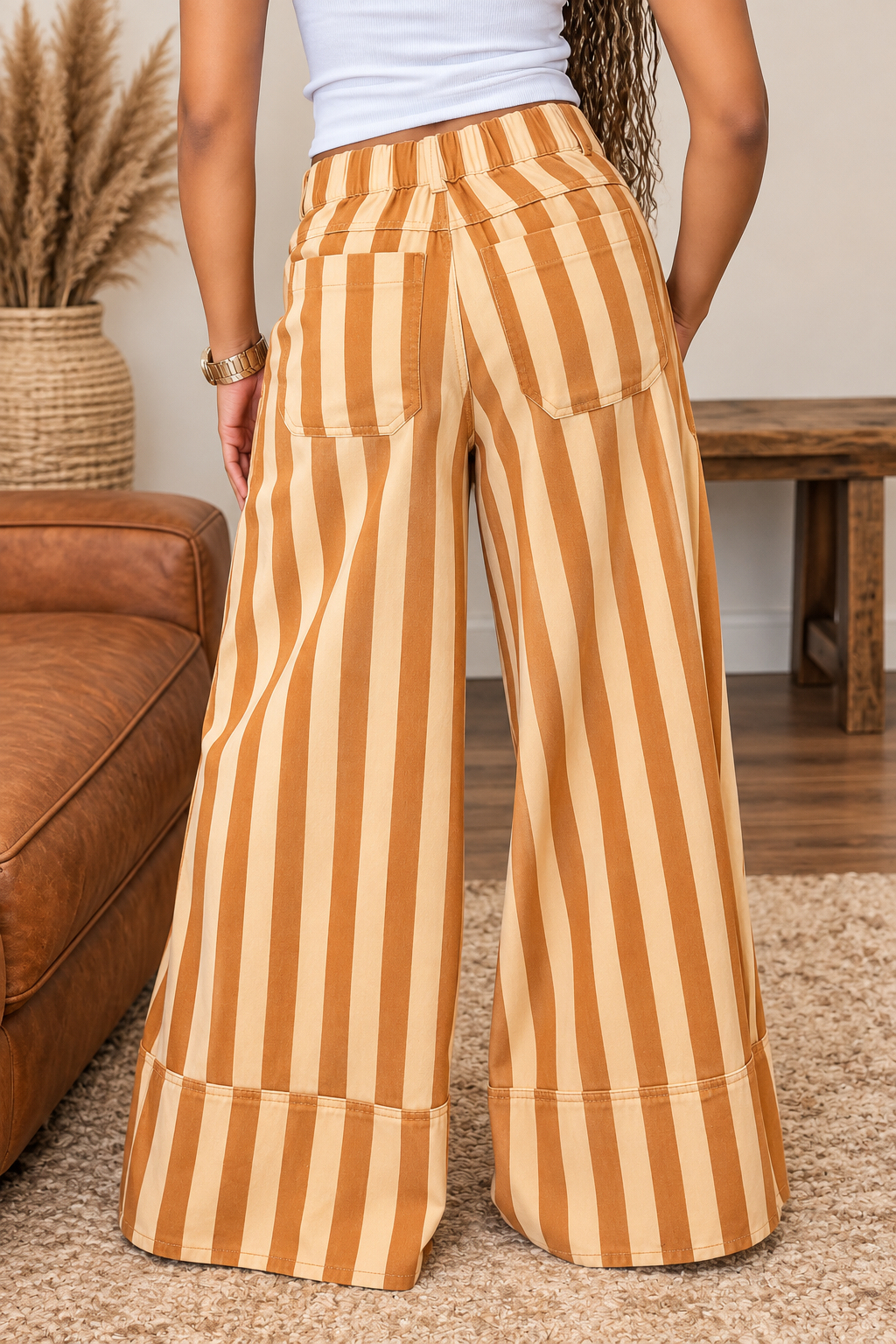 Back view of mustard and cream striped wide-leg pants showing back patch pockets and deep cuffed hems.