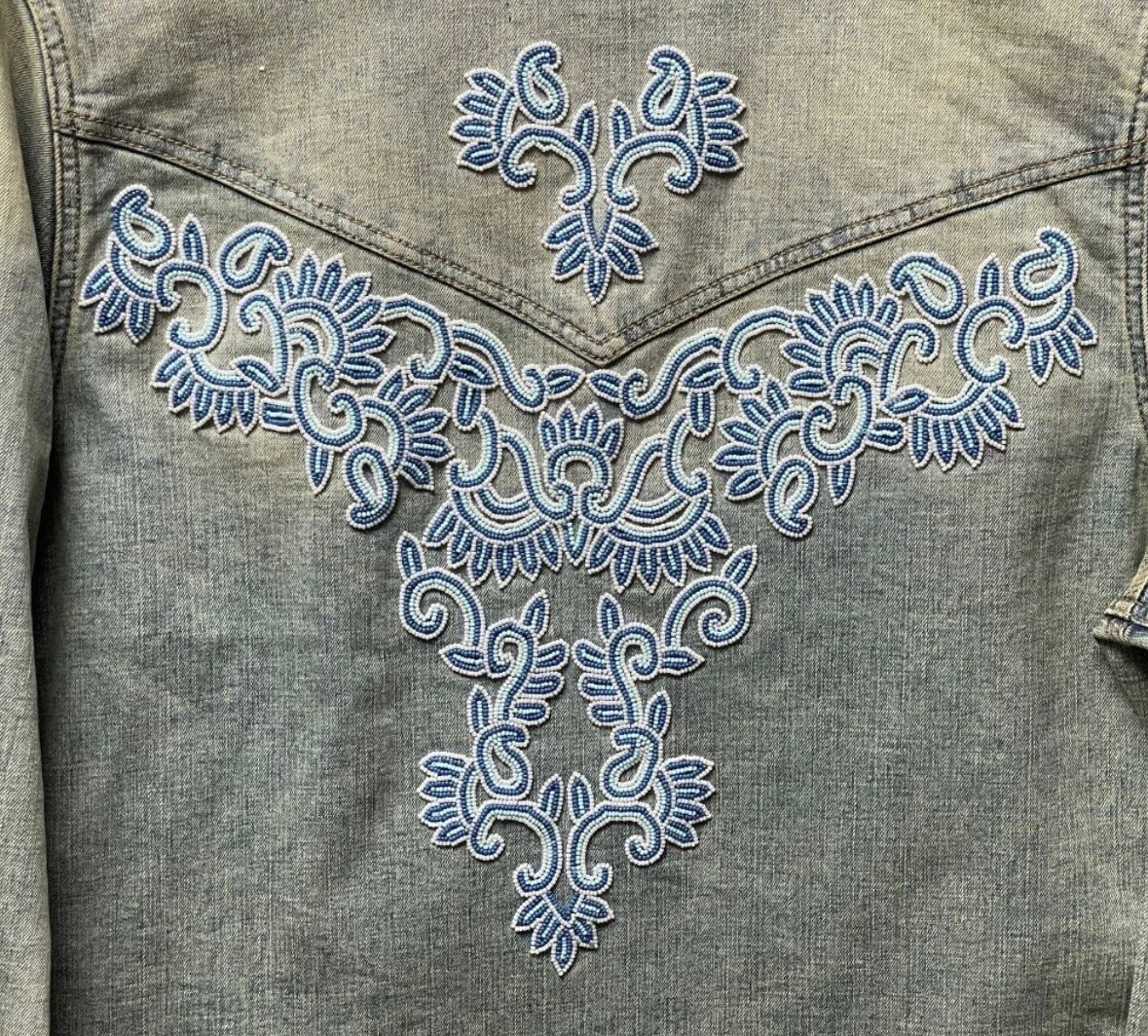 Close-up of the Scully denim jacket’s back, showing blue and white scroll motifs across the pointed Western yoke.