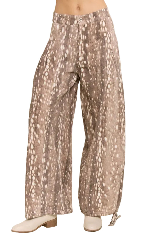 Front view of a model wearing taupe fawn print wide leg pants with cream spots, front pockets, and belt loops.