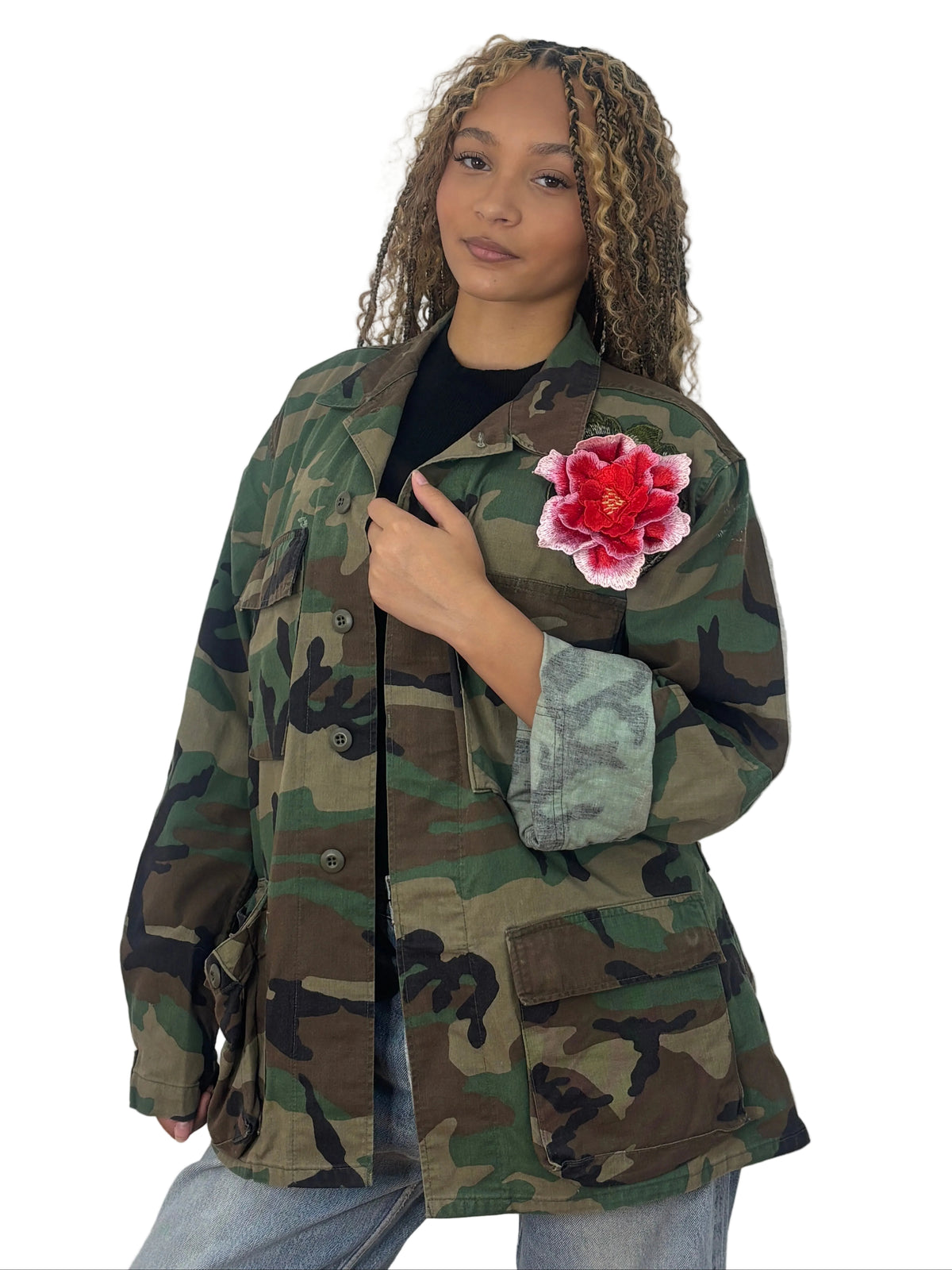Front view of vintage camouflage field jacket with a red and pink floral appliqué on the chest and large flap pockets
