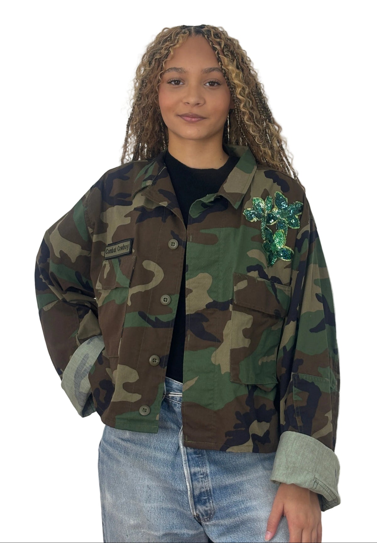 Front view of cropped vintage camouflage jacket with a green sequin appliqué on the chest, buttons, and flap pockets