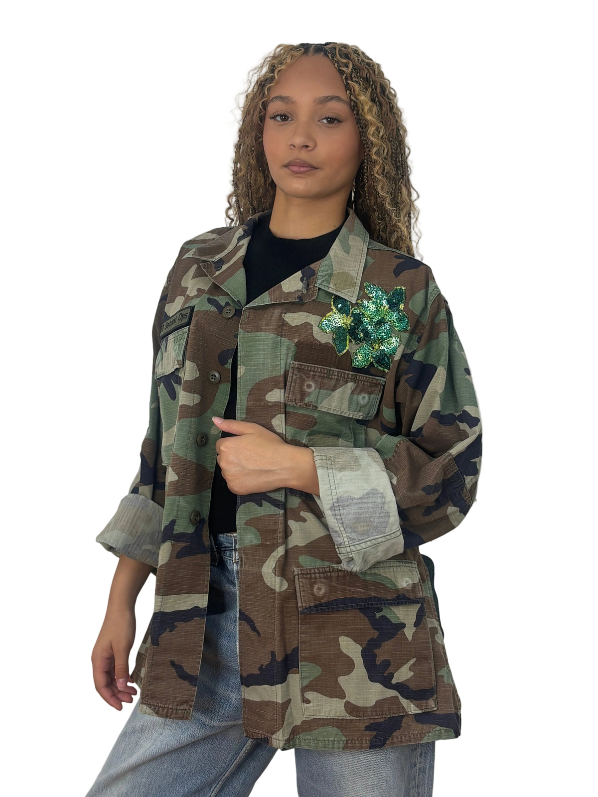 Front view of vintage camouflage field jacket with a green sequined flower appliqué on the chest and large flap pockets