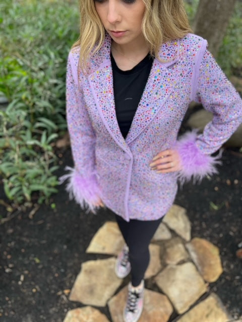Model wearing a lavender rhinestone Queen of Sparkles blazer with feather cuffs outdoors, shown from shoulders to shoes.