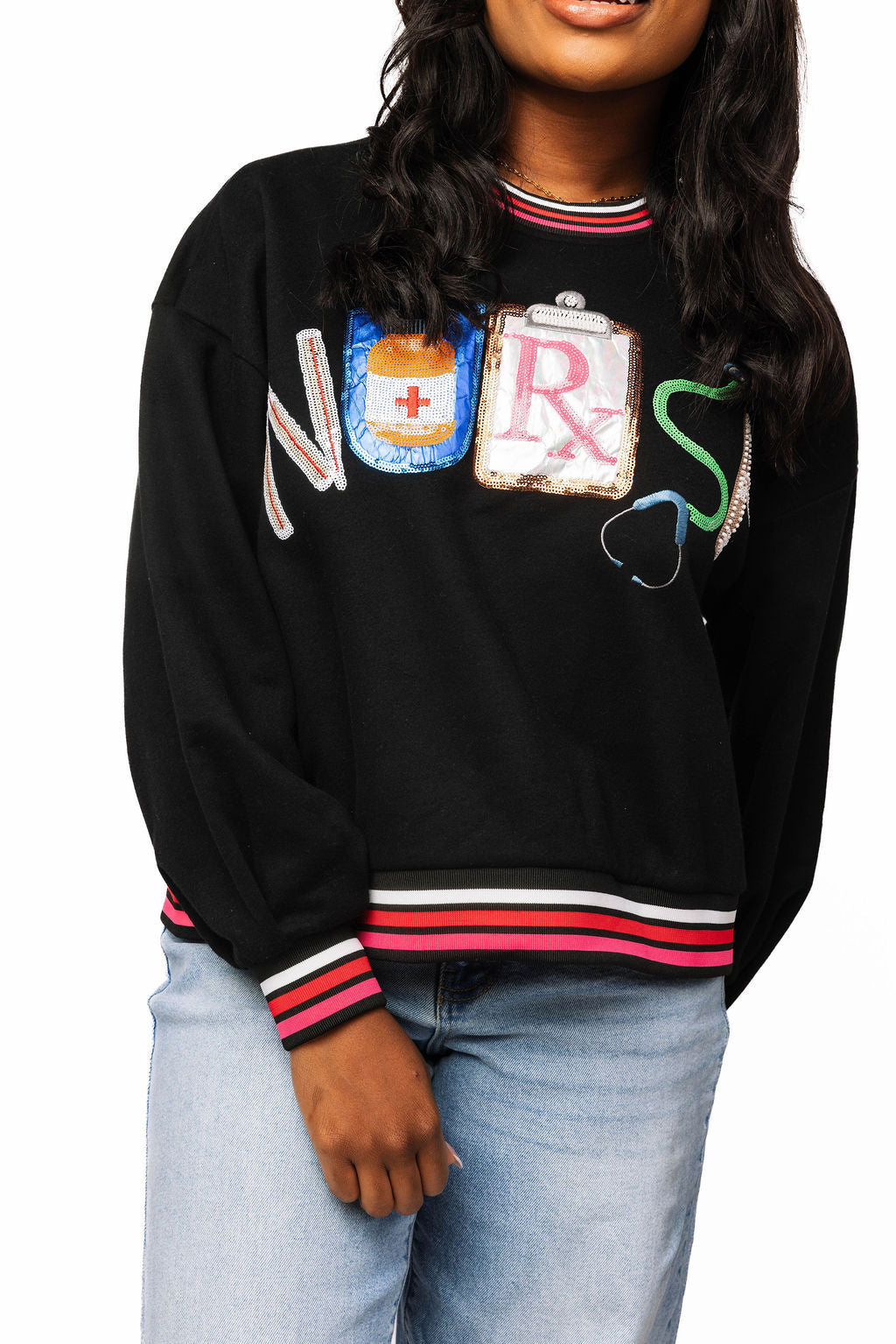 Front view of a model wearing the Queen of Sparkles nurse sweatshirt with colorful medical-themed lettering and striped ribbed trim.