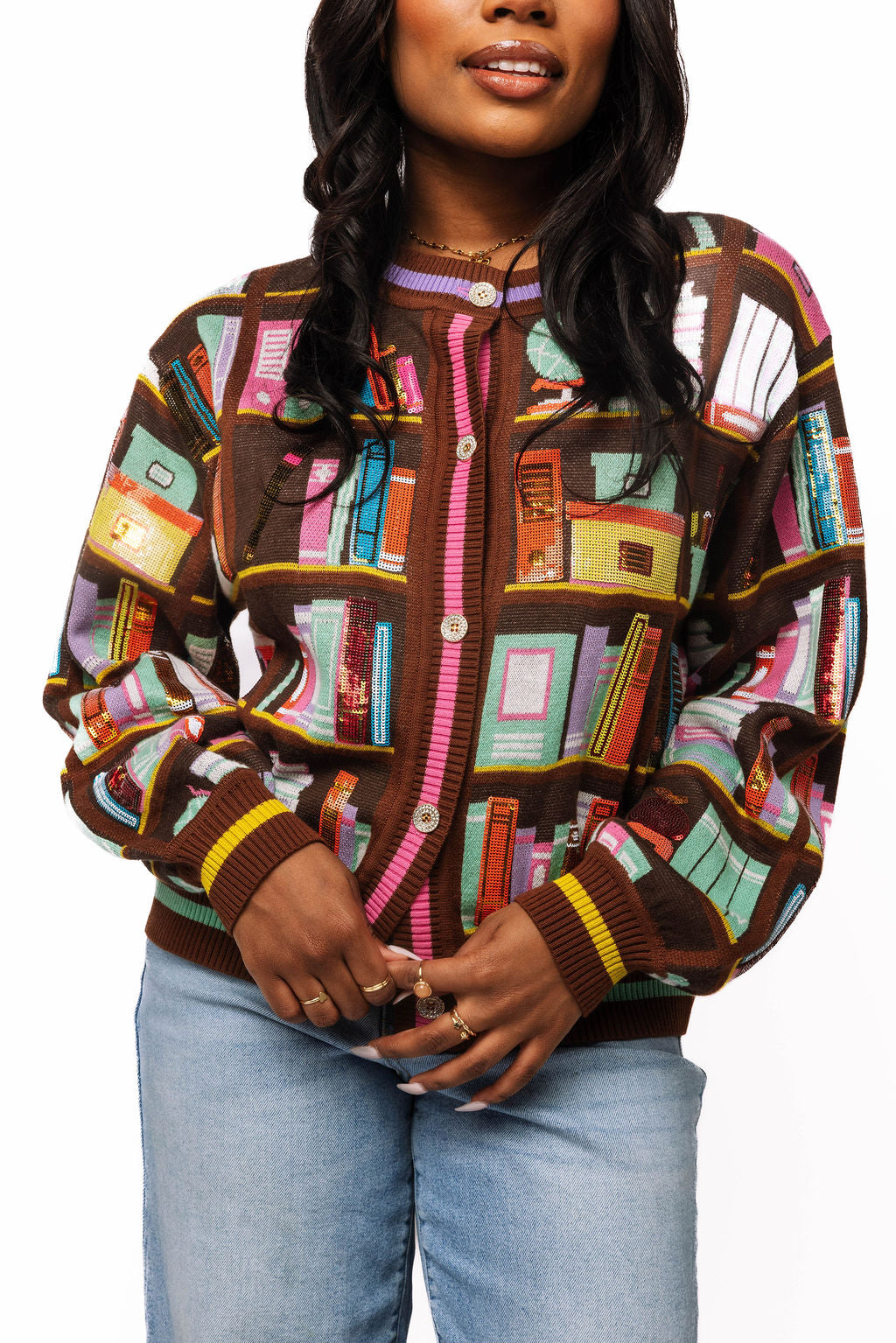 Model wearing a brown Queen of Sparkles button-up cardigan with colorful library book designs, front view