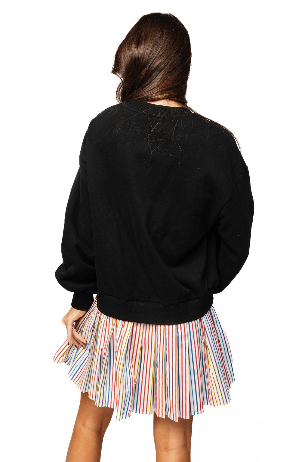 Back view of a model wearing the Queen of Sparkles black sweatshirt dress, showing the plain sweatshirt back and pleated multicolor striped skirt.