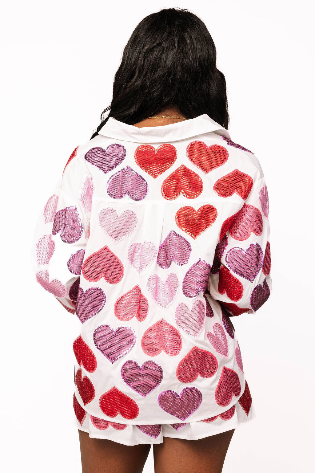 Back view of the white button-up top, showing red, pink, and purple sparkling heart shapes across the back and sleeves.