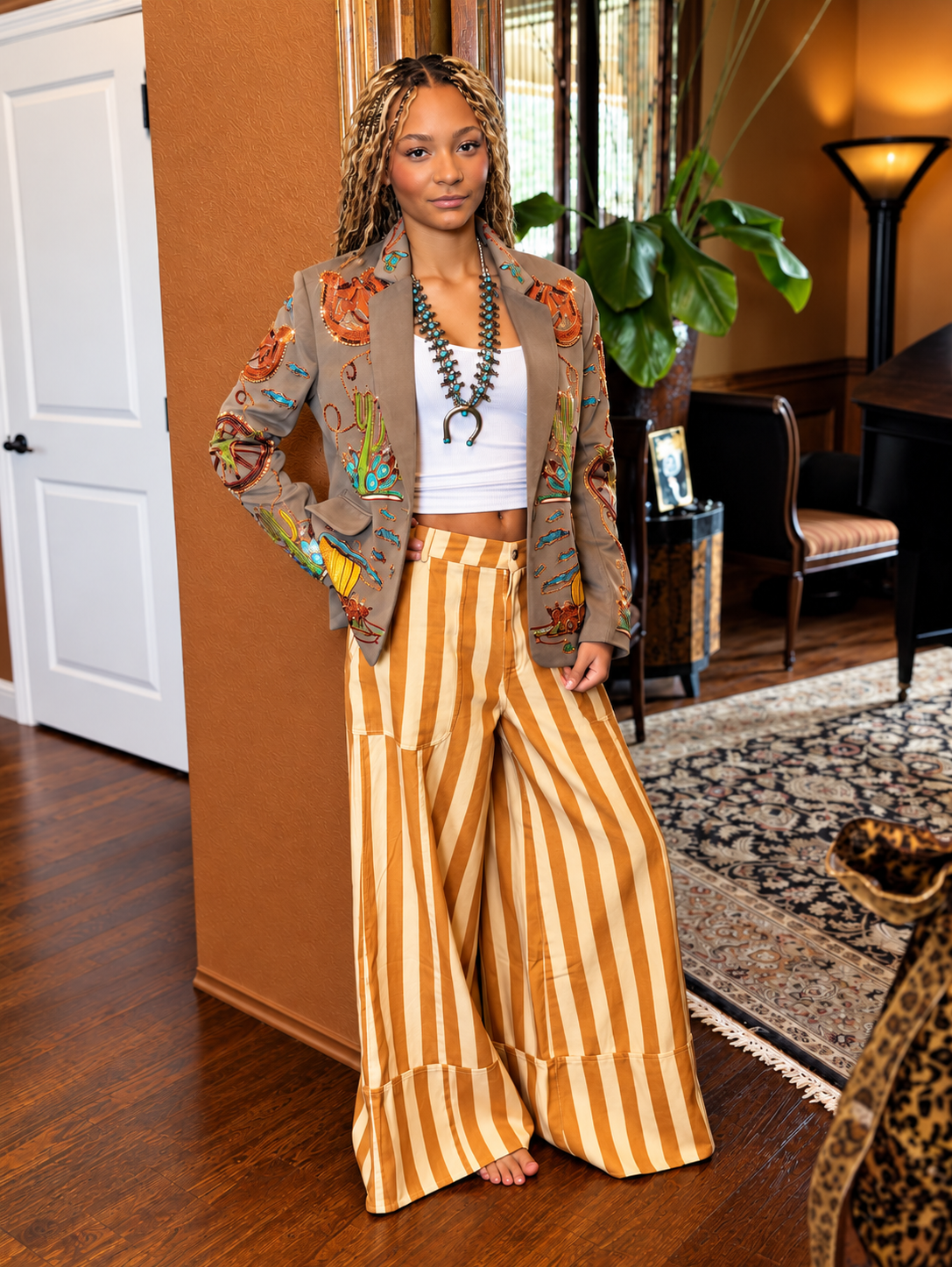 Model styling mustard and cream striped wide-leg cuff pants with an embroidered jacket and turquoise necklace.