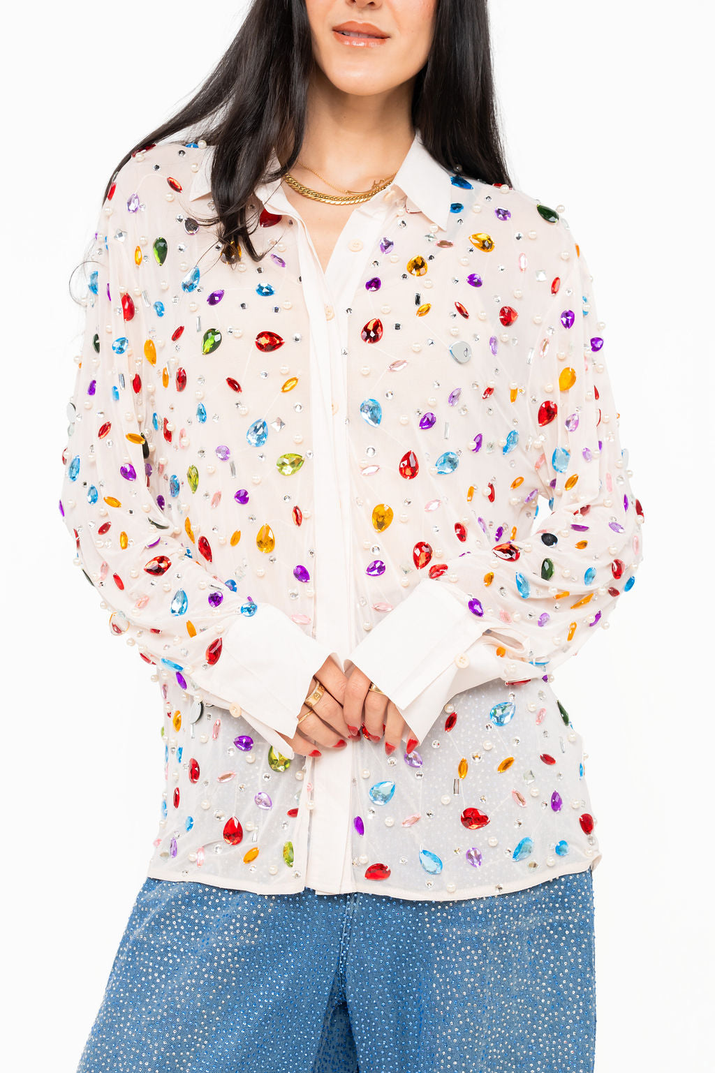 Front view of the Queen of Sparkles white long-sleeve button-up top with colorful jewel and pearl embellishments, modeled with blue denim.