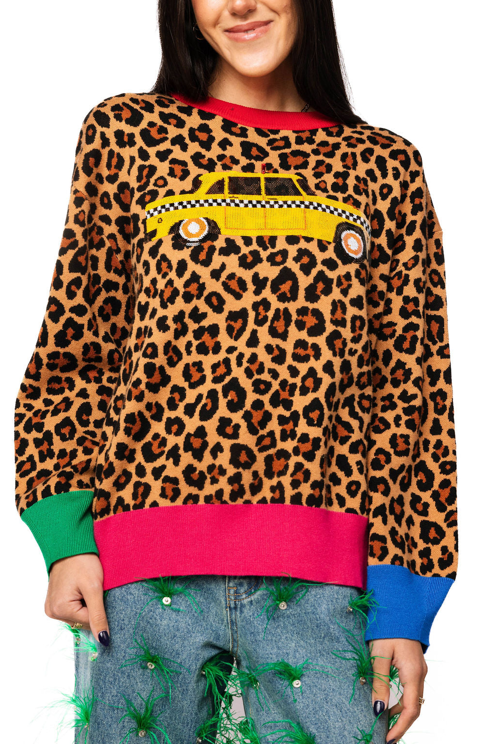 Front view of a model wearing the Queen of Sparkles leopard-print sweater with a yellow taxi graphic, pink trim, and green and blue cuffs.