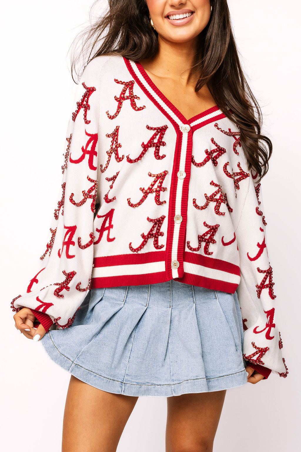 Model wearing the white Queen of Sparkles Alabama cardigan, front view showing repeating crimson Alabama A motifs and red trim.