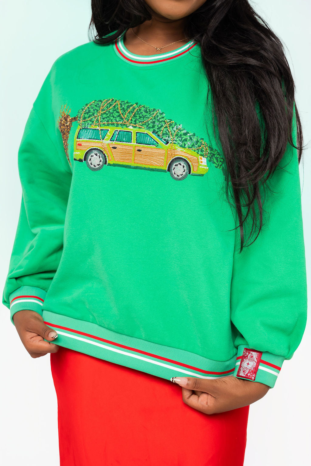 Queen of Sparkles licensed green sweatshirt with a sequin and beaded station wagon carrying a Christmas tree, with red and white striped trim.