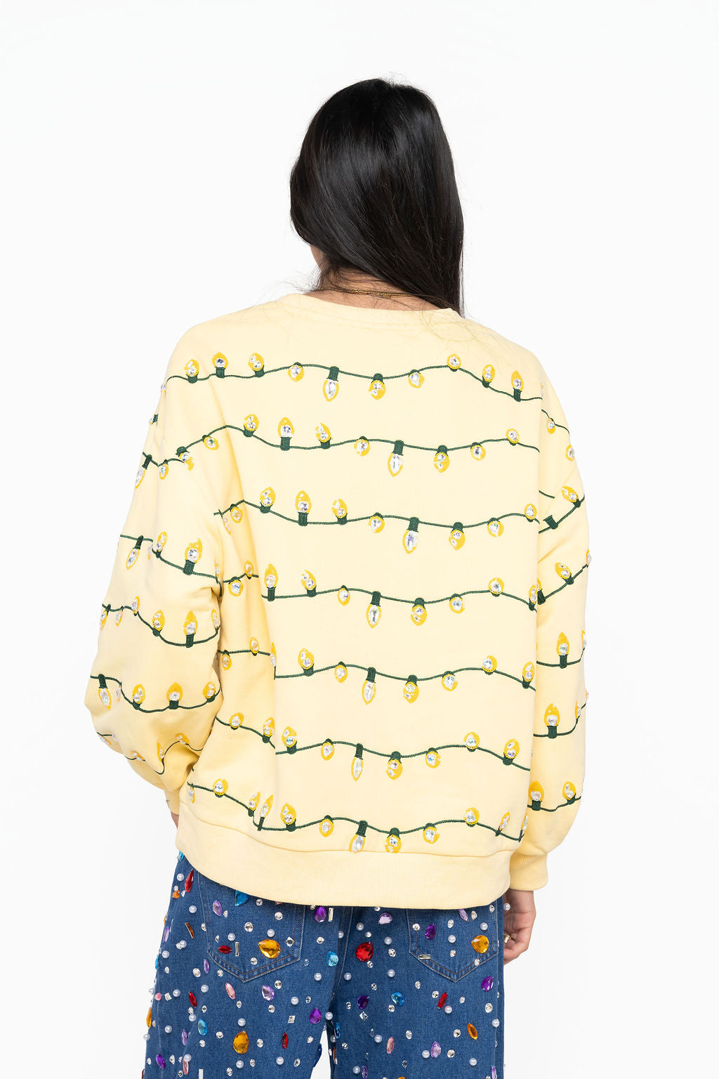 Back view of Queen of Sparkles yellow sweater with rows of sequin Christmas lights on green cords across the back and sleeves.