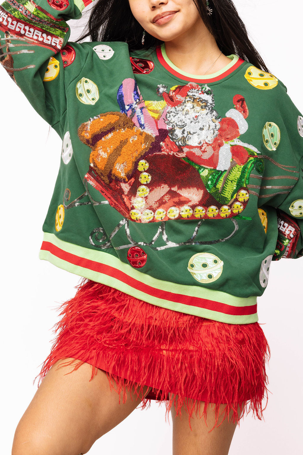 On-model front view of the deep green Queen of Sparkles sweatshirt with a sequined Santa and sleigh graphic, holiday motifs, and red-and-lime trim.