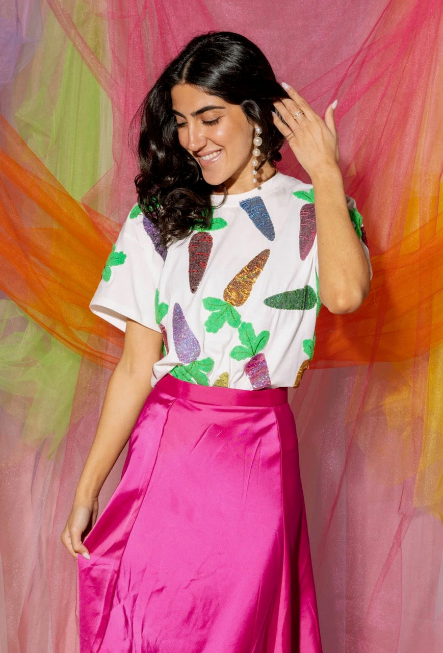 Full-length front view of a model wearing the Queen of Sparkles white short-sleeve tee with colorful sequined carrot motifs, styled with a magenta skirt.
