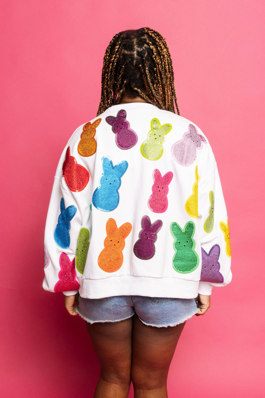 Back view of a model wearing the Queen of Sparkles white sweatshirt with colorful sequin Peeps characters across the back.