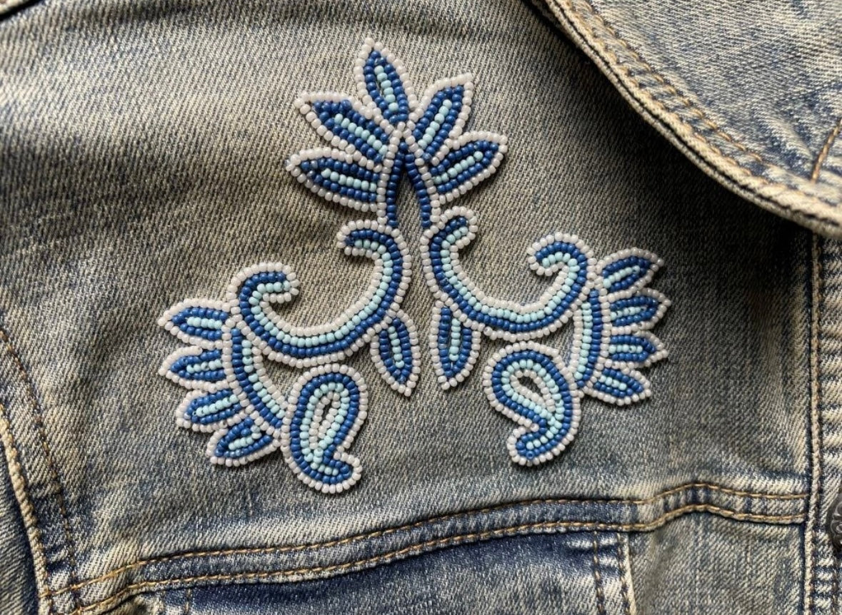 Close-up of blue and white beadwork in a floral scroll motif on the Scully light-wash denim jacket.