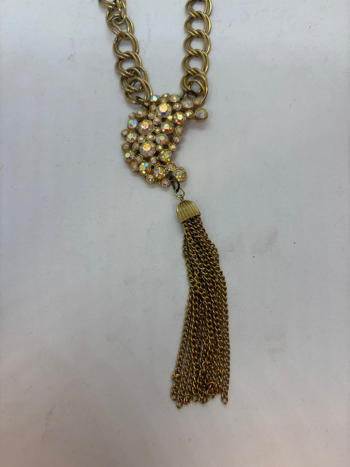 Close-up of repurposed vintage aurora rhinestone brooch and gold chain tassel necklace