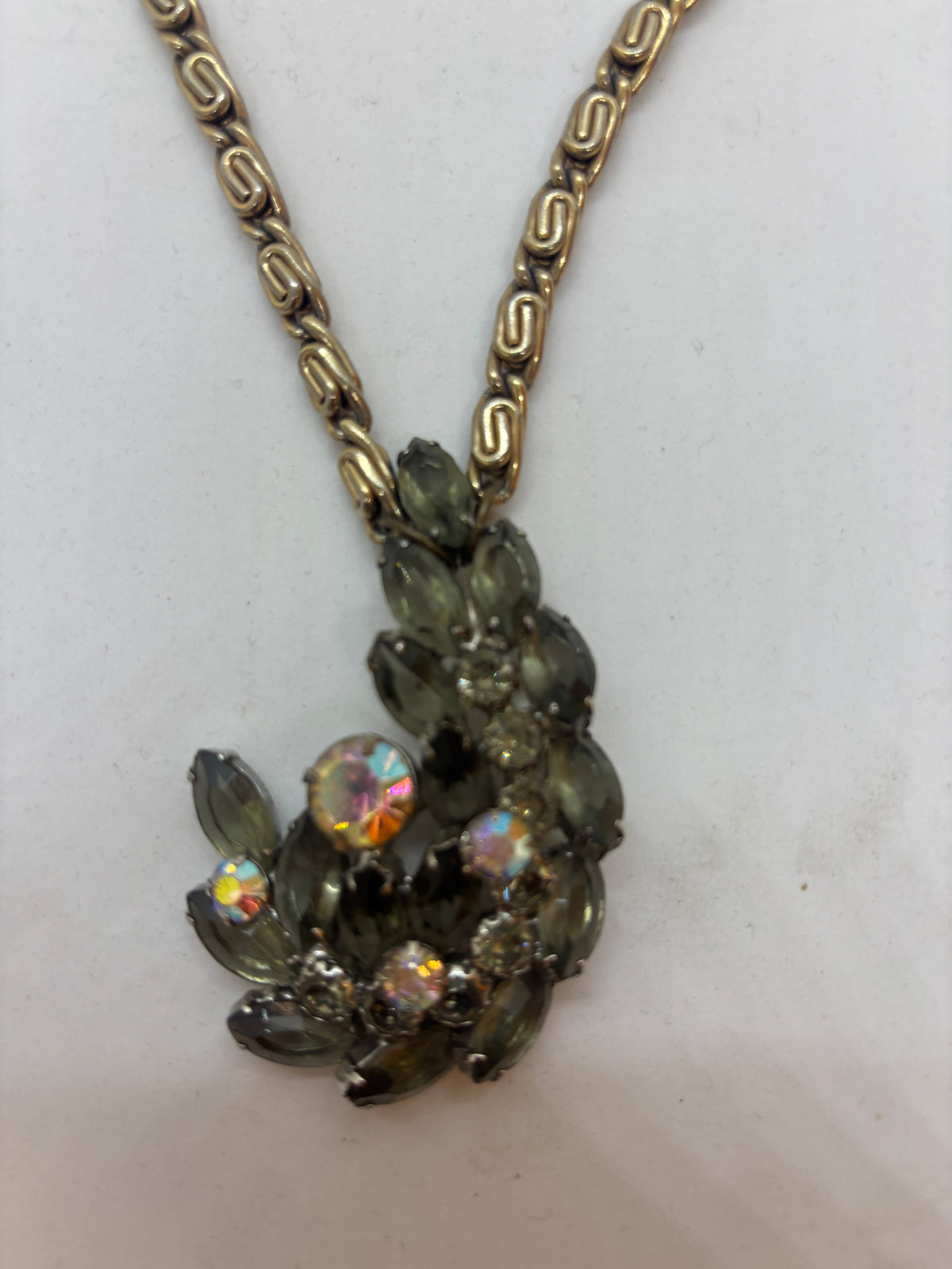 Close-up of repurposed vintage brooch featuring smoky olive-green marquise stones and iridescent rhinestones.