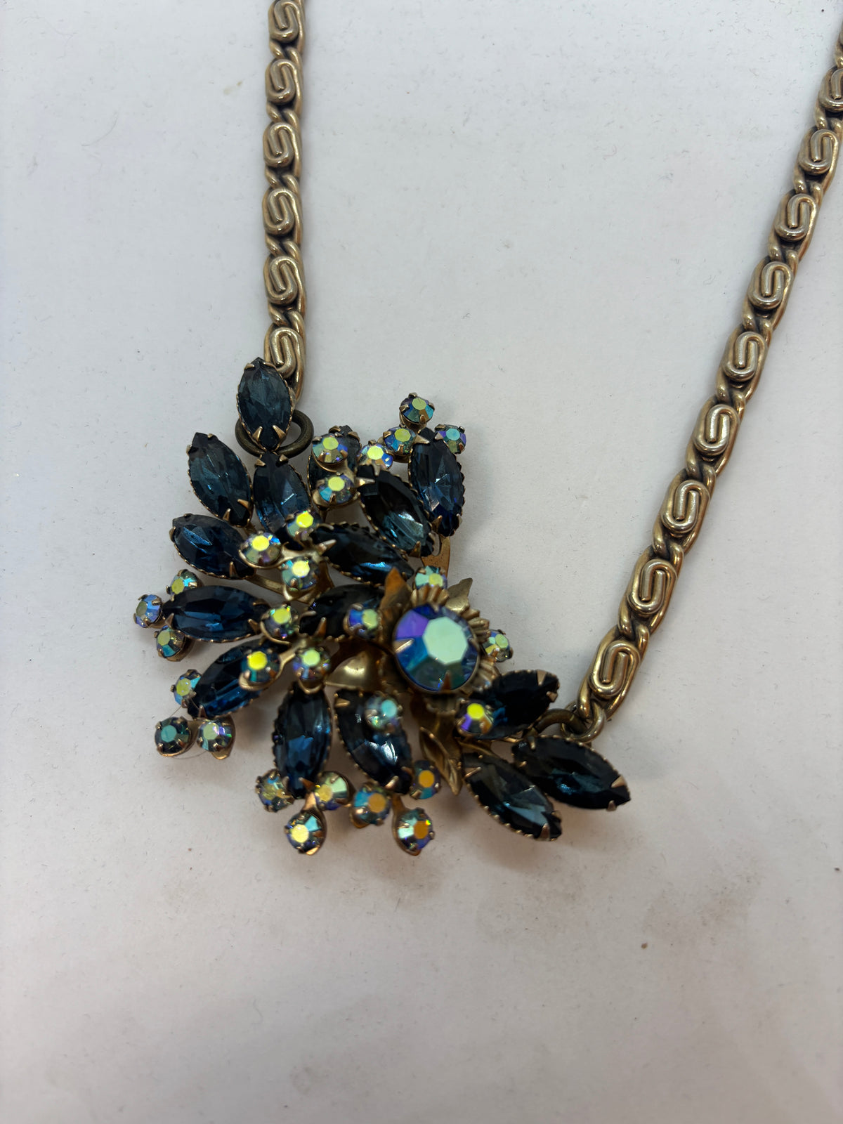 Close-up of vintage floral brooch with deep blue marquise rhinestones and sparkling aurora borealis crystals.