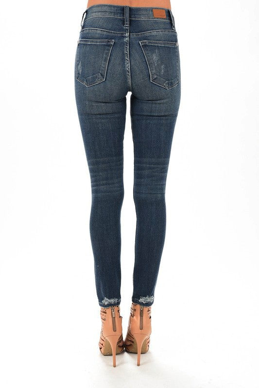 Full-length back view of the dark-wash Judy Blue skinny jeans with back pockets and frayed ankle hems.