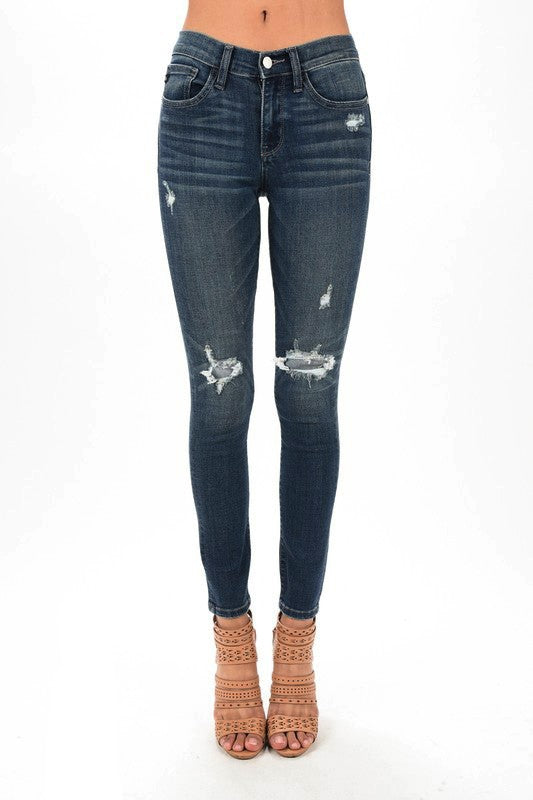 Full-length front view of dark-wash Judy Blue skinny jeans with distressed star patches at the knees.